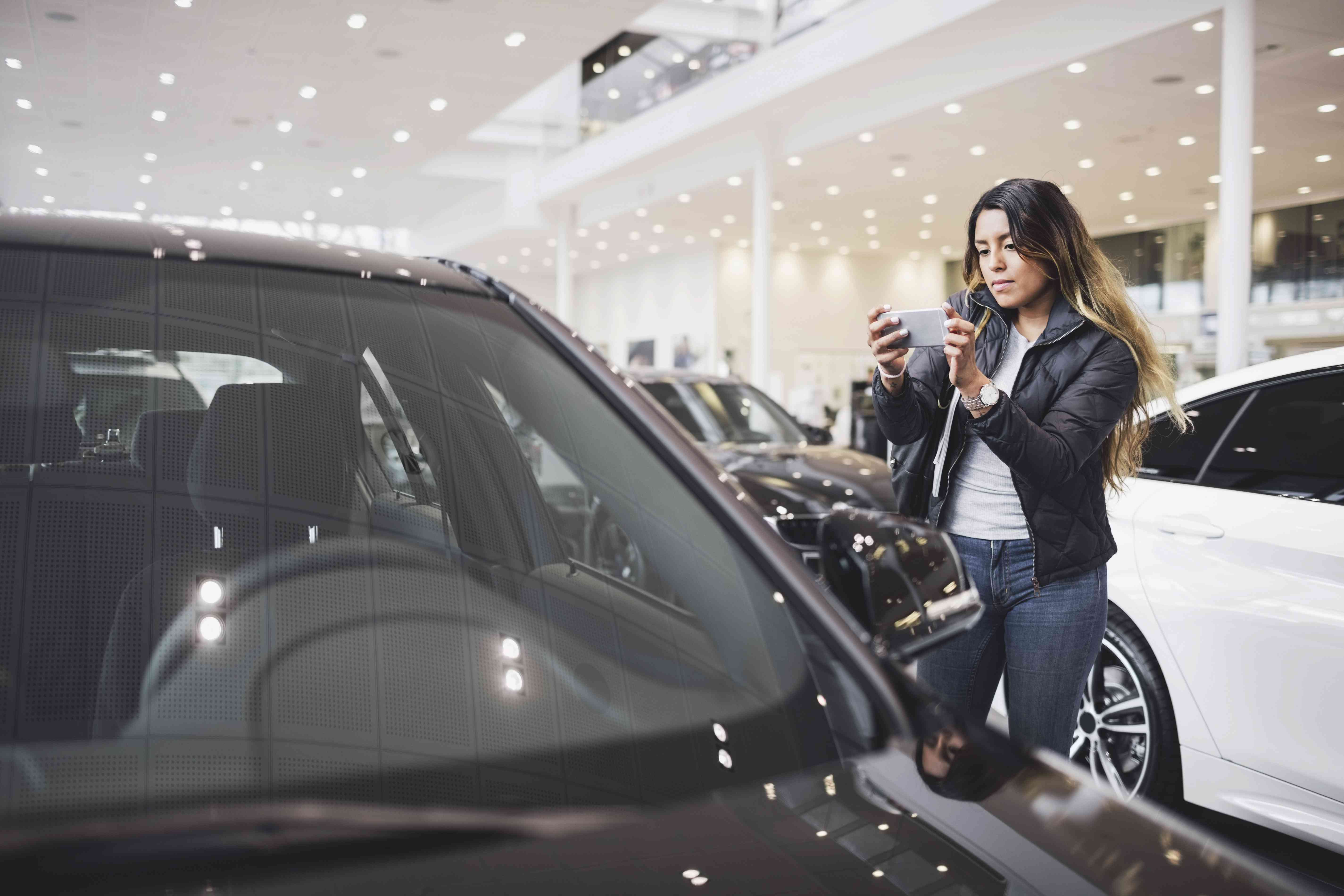 A woman looks at cars in a showroom.