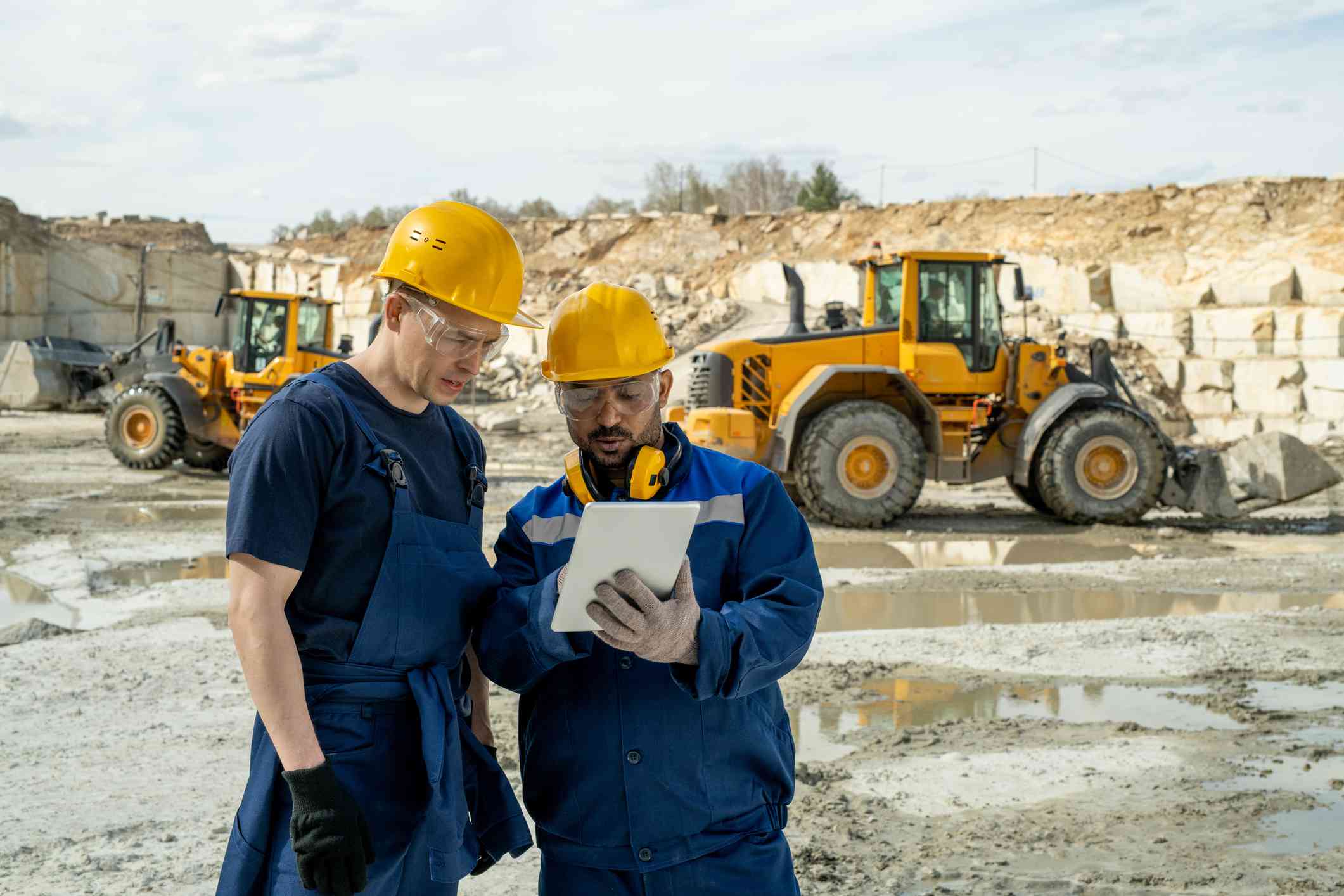 Two construction workers review information on a job site.