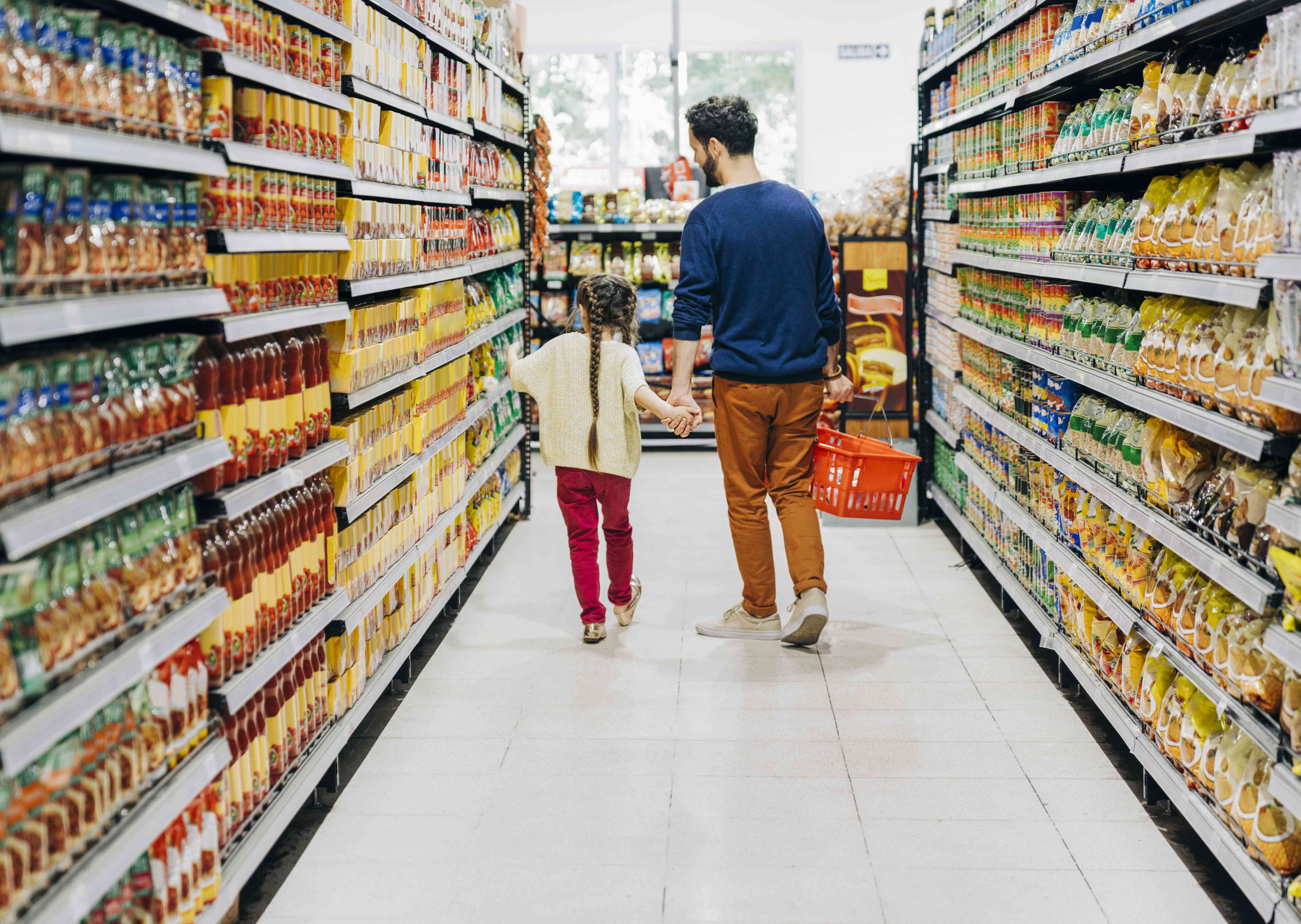 Father and daughter walking down a grocery aisle.