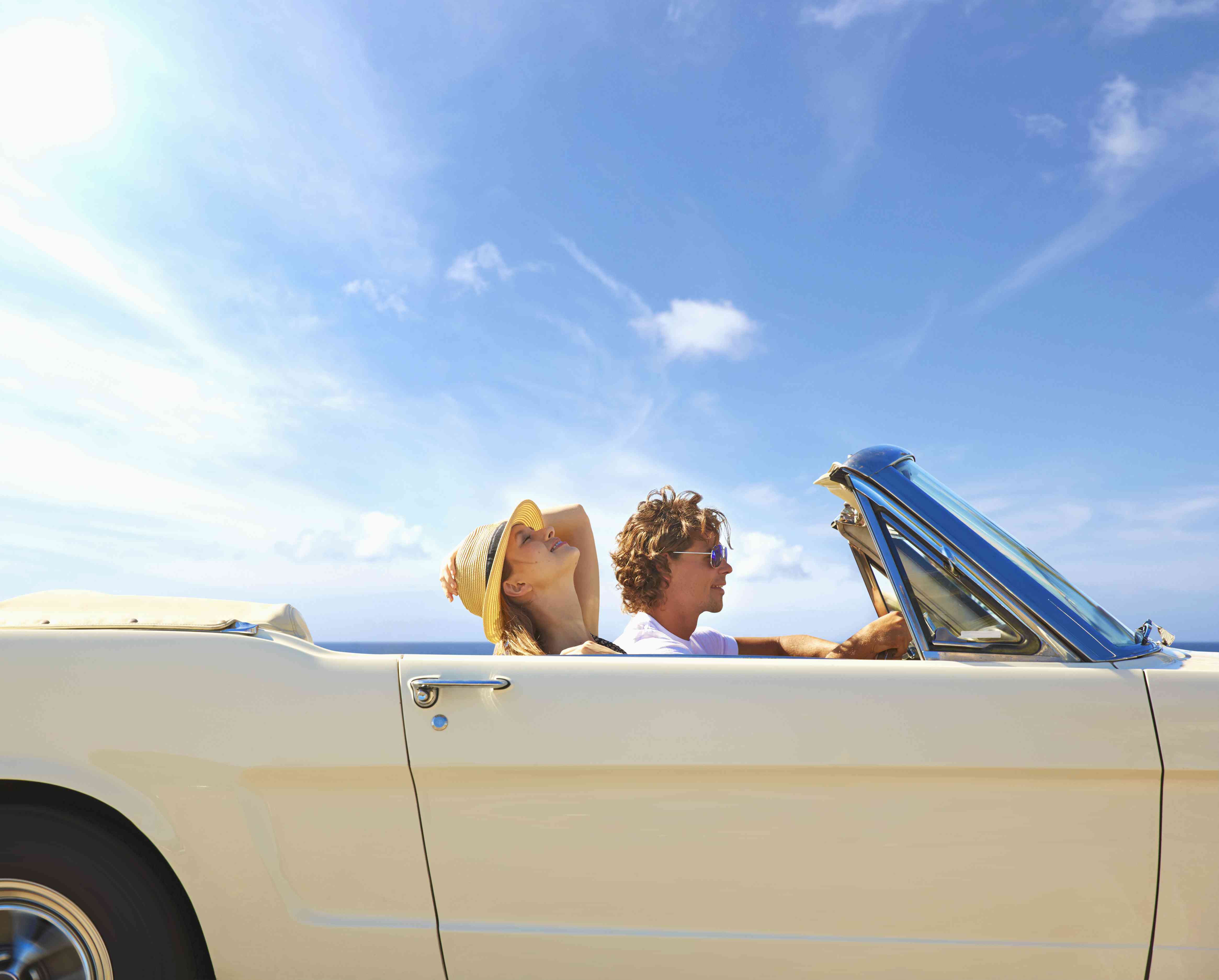 couple driving in a convertible on a sunny day
