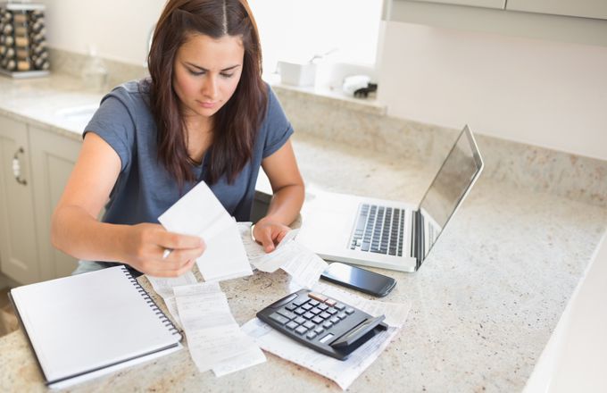 Woman with bills and calculator at laptop