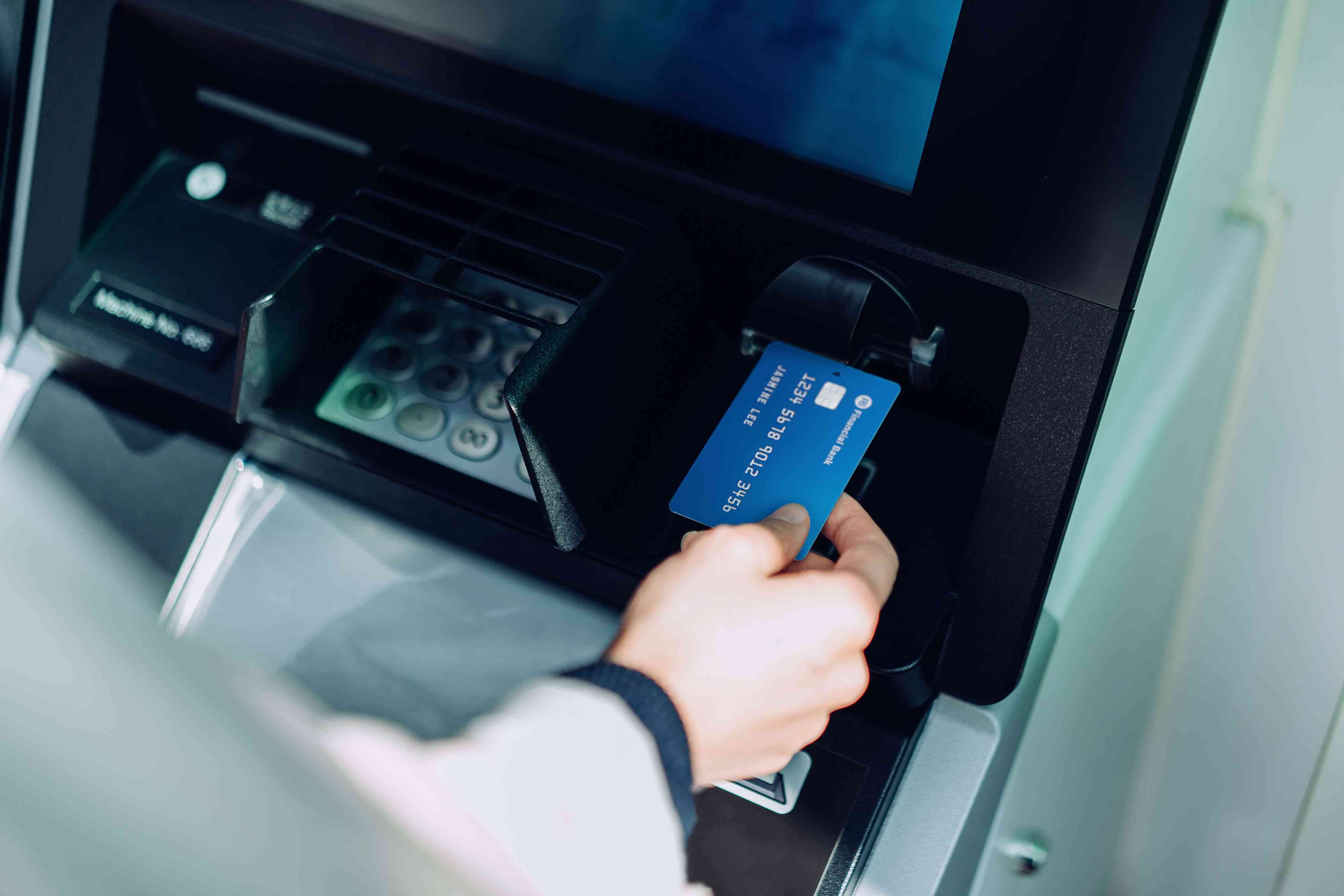 Close up of young woman inserting her bank card into automatic cash machine in the city