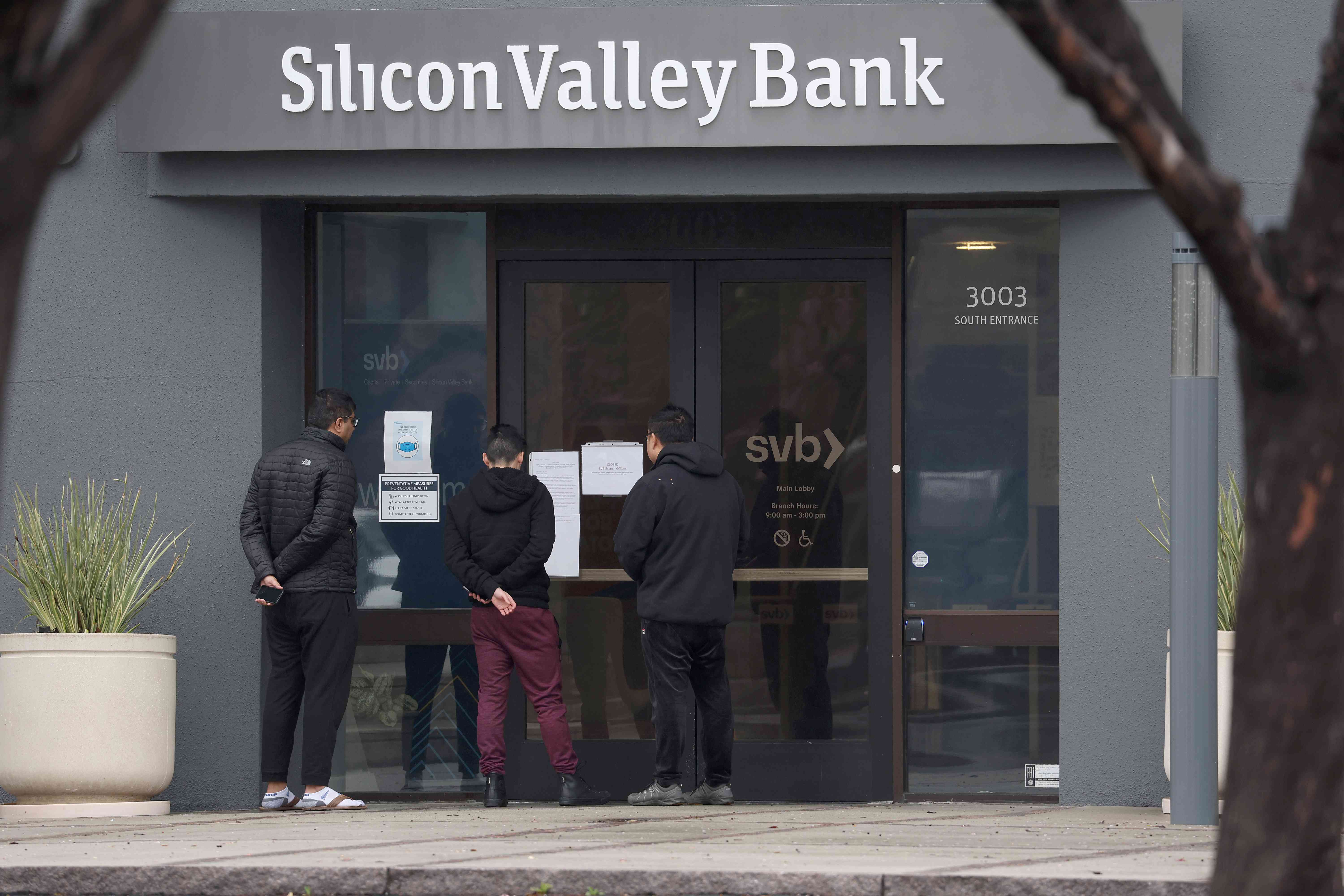 SANTA CLARA, CALIFORNIA - MARCH 10: Employees stand outside of the shuttered Silicon Valley Bank (SVB) headquarters on March 10, 2023 in Santa Clara, California. Silicon Valley Bank was shut down on Friday morning by California regulators and was put in control of the U.S. Federal Deposit Insurance Corporation. Prior to being shut down by regulators, shares of SVB were halted Friday morning after falling more than 60% in premarket trading following a 60% declined on Thursday when the bank sold off a portfolio of US Treasuries and $1.75 billion in shares to cover declining customer deposits.